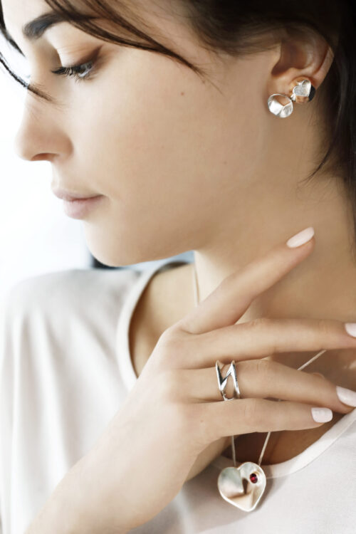Uus kollektsioon Hertz. Modell kannab hõbedast südamekujulist ripatsit hõbeketiga ja südamekujulisi kõrvarõngaid ning hõbesõrmust.